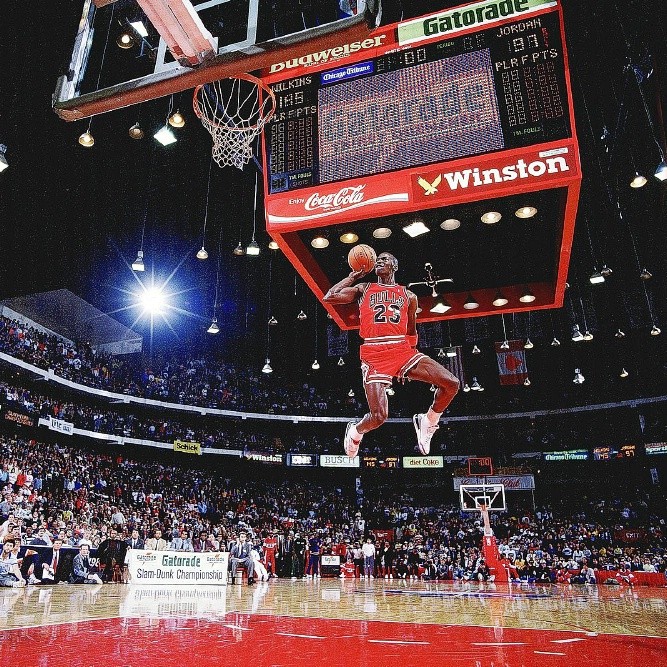 81. Michael Jordan: Bức ảnh chụp ngày 8/2/1988. Trong tuần lễ NBA All-Star (bầu chọn đội hình tiêu biểu và chơi trận đấu biểu diễn giữa hai đội Các ngôi sao miền Tây và miền Đông), giải Slam Dunk được tổ chức với sự xuất hiện của 7 đấu thủ, trong đó đáng chú ý nhất là Dominique Wilkin và Michael Jordan. Wilkin vô địch Slam Dunk Contest năm 1986 và Jordan vô địch năm 1987, nhưng họ chưa từng đối đầu nhau trực tiếp. Lần này, họ cùng lọt vào vòng cuối cùng và trực tiếp đối mặt nhau. Wilkin ghi 148 điểm và buộc Jordan - với 99 điểm - phải bước vào lượt dunk cuối của mình với nhiệm vụ ghi 50 điểm tối đa để chiến thắng (Wilkin hơn điểm Jordan ở các vòng trước). Trước thách thức này, Jordan quyết định mạo hiểm: Anh dắt bóng từ cuối sân bên kia và chạy cho tới khi chân chạm vạch ném phạt ở khoảng cách 8m. Jordan bật lên với một tay cầm bóng và dunk thành công để ghi 50 điểm và chiến thắng. Cú dunk lịch sử này đánh dấu sự ra đời của “Air Jordan”, tên một thương hiệu giày thể thao và cũng là nickname của MJ.